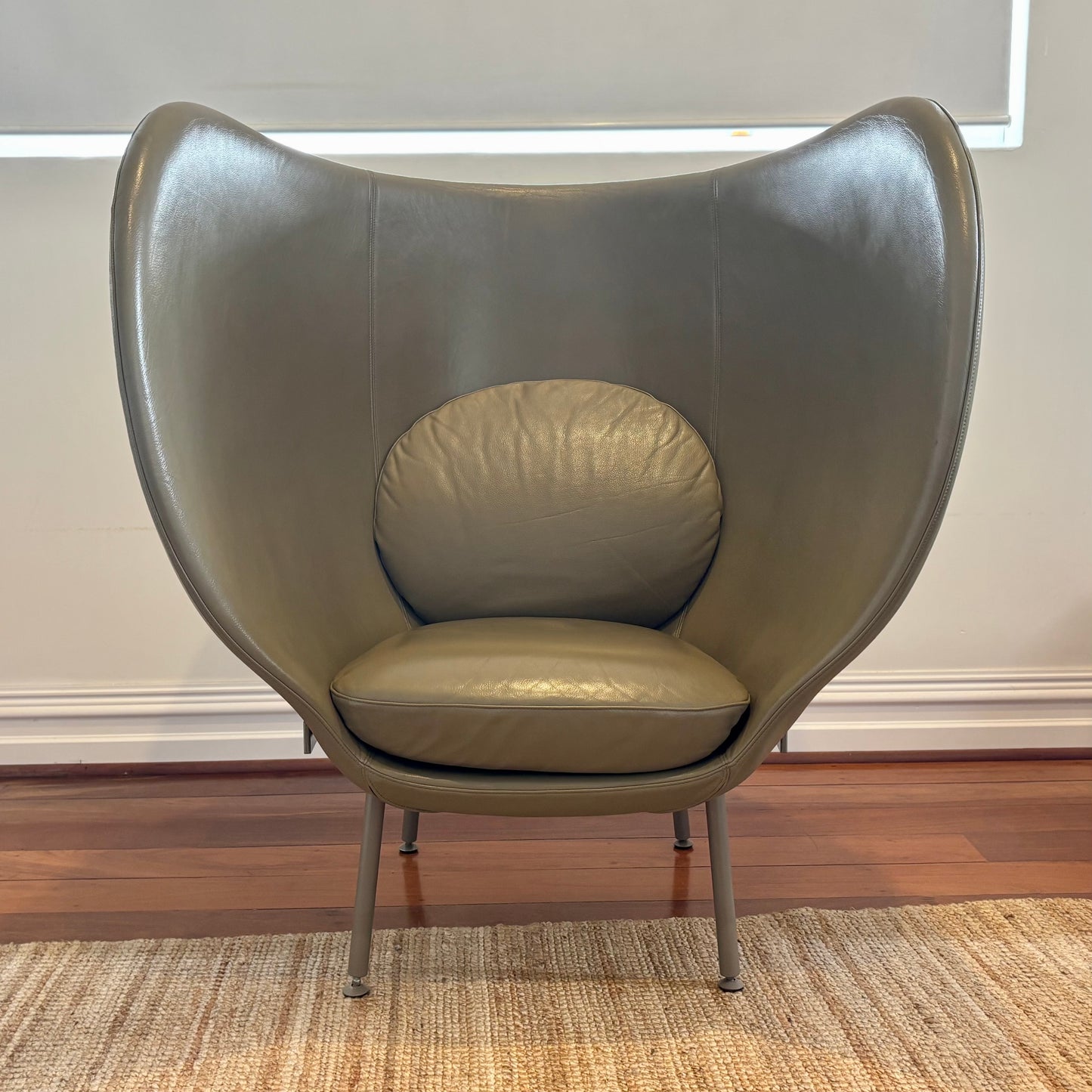 Modern olive green chair on a wooden floor with a neutral wall background