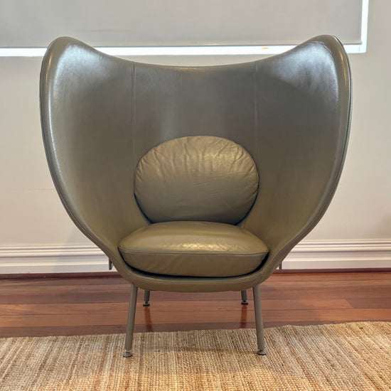 Modern olive green chair on a wooden floor with a neutral wall background