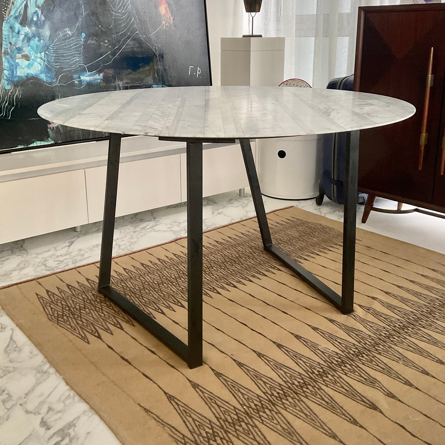 Round marble table with black metal legs in a modern interior setting.