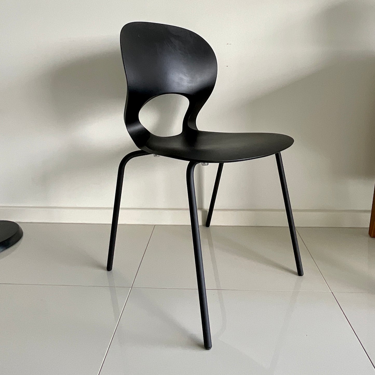 Black chair on a tiled floor with a plain white wall background