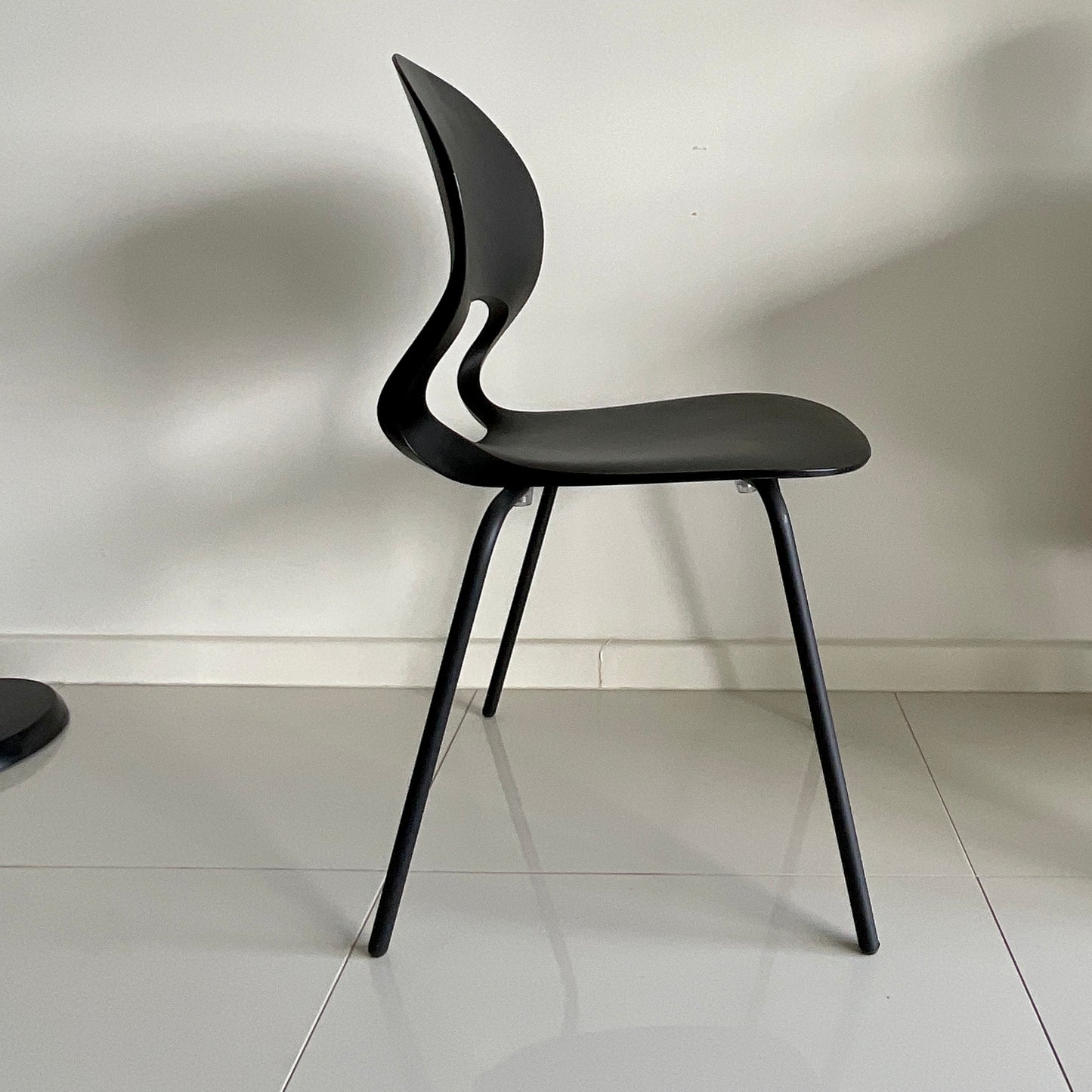Black modern chair on a white floor with a white wall background