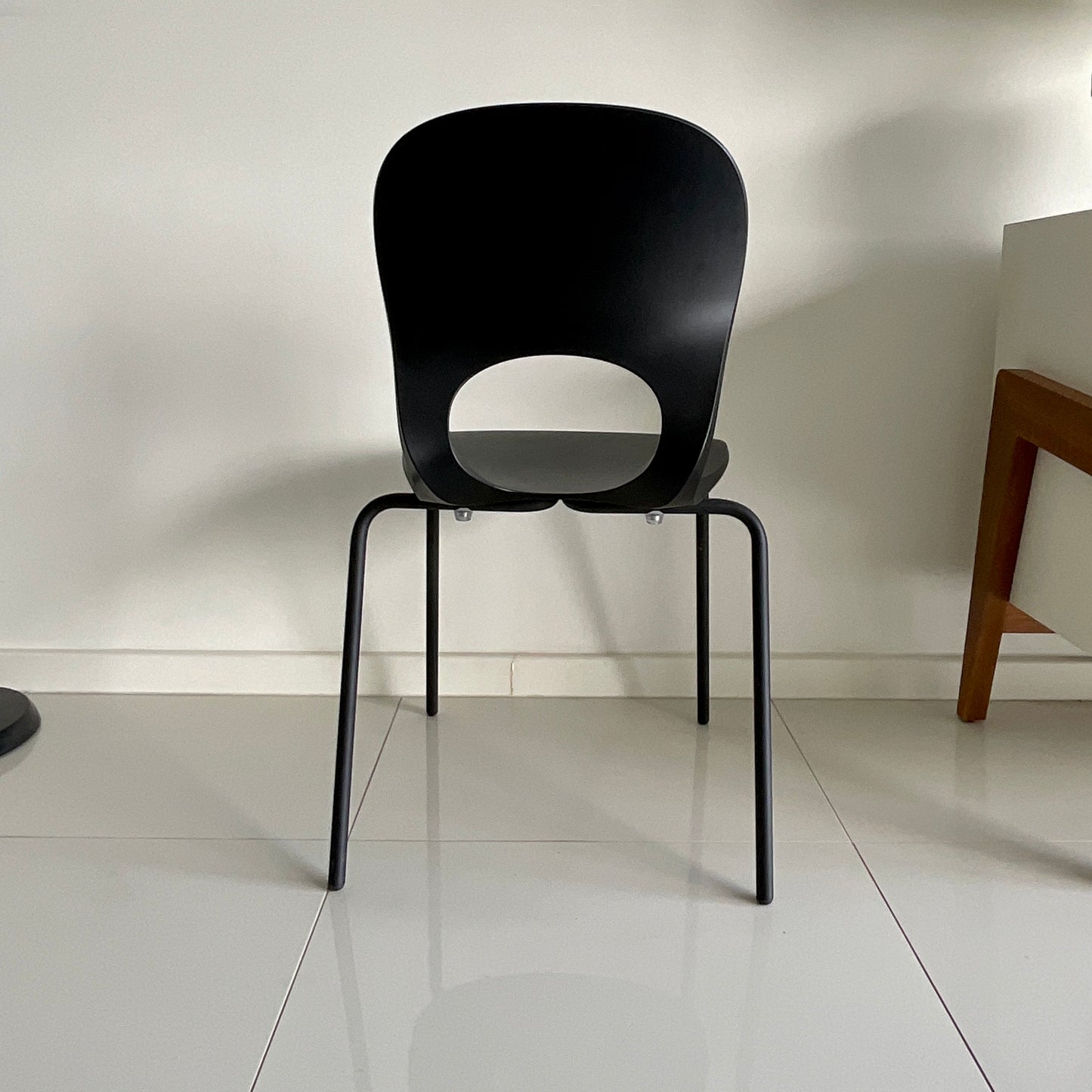 Black chair on a white floor with a neutral wall background